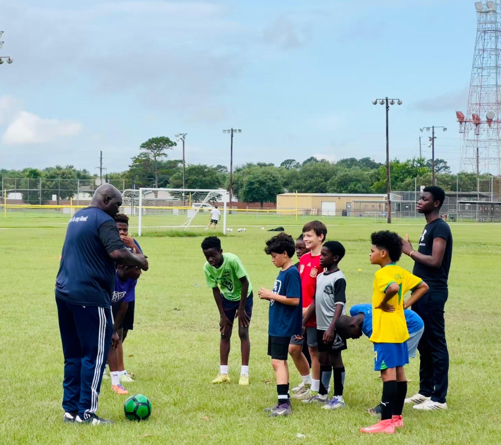 A Redeemer Sports coach talking with a group of young players during a training session