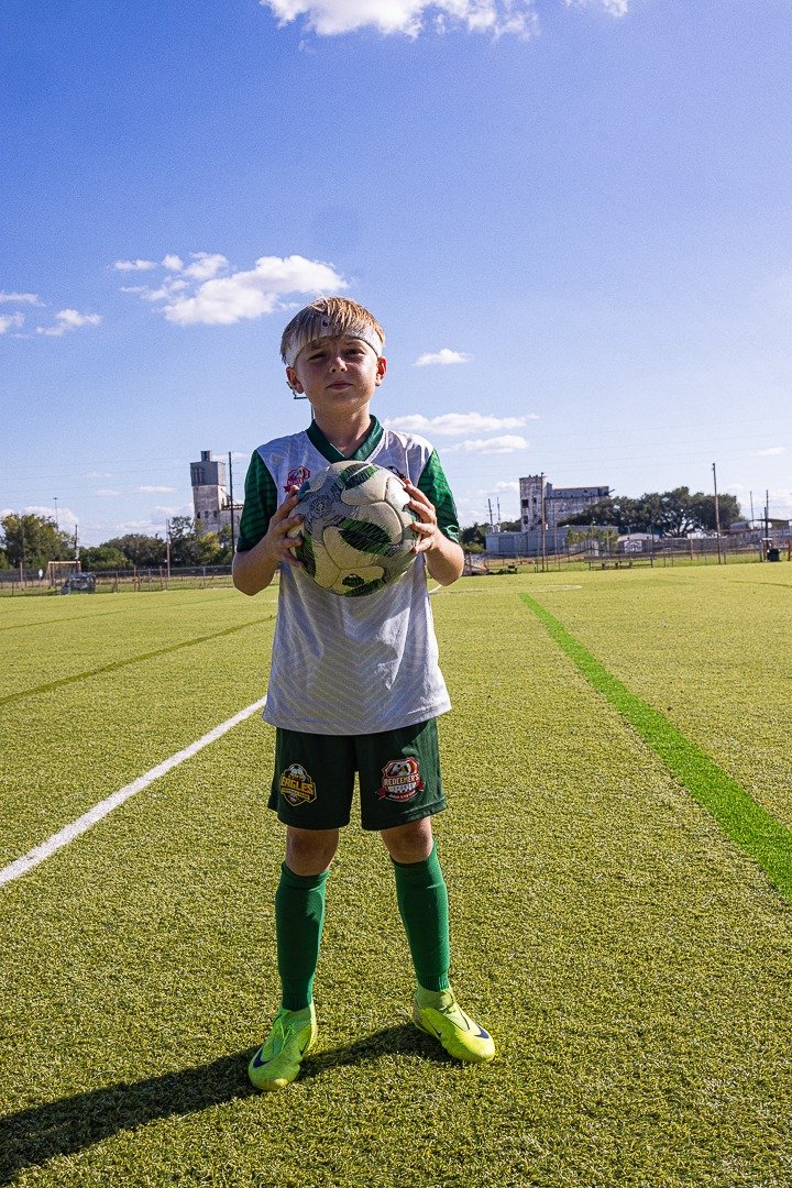 A Redeemer Sports youth soccer player holding a match ball on the turf